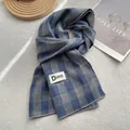 Primer plano de bufanda a cuadros azules con costura fina y etiqueta de marca - 180*60cm / Azul Niebla