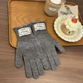 Close-up of gray knit gloves with ruffled cuffs and floral label on a wooden tray - Gray