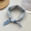 Close-up of blue and white striped cotton scarf tied in a knot on a white textured rug - Sky Blue