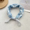Close-up of light blue paisley print silk scarf tied in a stylish knot on a white textile - 58*58cm / Paisley White Blue