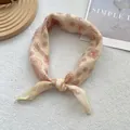 Detail of beige paisley silk scarf tied in a loop on a white textured background - 58*58cm / Paisley Yellow