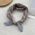 Gros plan d'un foulard carré en soie légère avec carreaux vintage et fleurs - café