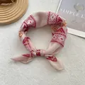 Close-up of bohemian silk scarf with colorful geometric patterns tied in a decorative knot - 58*58cm / Red