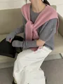 Detail of grey knitted top with sleeves and pink shawl layered on white pants - Pink
