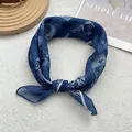 Detailed close-up of navy blue paisley silk scarf with white floral patterns and texture - Blue Paisley