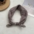 Primer plano de un pañuelo de algodón marrón con estampado paisley sobre fondo de revista - Cuadrado Grande / café
