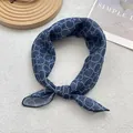 Close-up of blue and white floral silk scarf with polka dot patterns in a stylish knot - Blue Polka Dot Snowflake