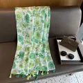 Détail d'un châle floral avec glands verts sur un canapé en cuir marron - 180cm x 90cm / Vert