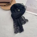 Detail eines schwarzen Spitzenschals mit feiner Blumenstickerei und Wellensaum - Schwarz
