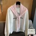 Détail d'un châle en laine rose à losanges superposé sur un sweat-shirt universitaire gris - Rose Sakura