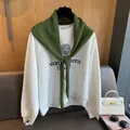 Détail du châle en laine matelassé vert olive porté sur un sweat-shirt gris de style rétro - Vert