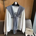 Close-up of grey knit shawl layered over a Northwestern University graphic sweatshirt - Gray