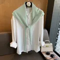 Dettaglio di uno scialle di lana verde chiaro sovrapposto a una camicia bianca in cotone - Verde Acqua