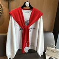 Detail of red knit shawl paired with a Northwestern sweatshirt on a white designer bag - Red