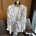 Detalle del pañuelo de algodón y lino con flores y elegantes borlas sobre un top blanco - Gris