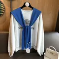 Detailansicht eines marineblauen Strickschals über einem grauen Varsity-Sweatshirt - Blau
