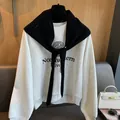 Detail showing knit wool diamond pattern shawl paired with a college print sweatshirt - Black