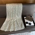 Detail van lichtgrijze chiffon sjaal met gouden bladmotieven op lederen ondergrond - 180*70 / Geelgroen