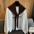 Detail of premium wool knit shawl with knot design over a university logo sweatshirt - Coffee