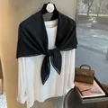 Détail d'un châle noir à pois noué sur un t-shirt blanc minimaliste à manches longues pour femme - Noir