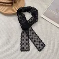 Primer plano de un pañuelo de encaje negro con bordados florales y bordes festoneados - Negro