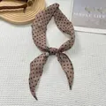 Bruine vintage zijden sjaal met stippen geknoopt in een strik op witte wafeltextuur achtergrond - Khaki