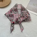Détail d'un foulard en soie à imprimé floral et bord roulé bordeaux sur tissu texturé - Jardin à pois