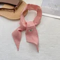 Detalle de bufanda de lino rosa con etiqueta artesanal sobre tela de gofre blanca - Rosa Coreano