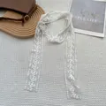 Dettaglio della sciarpa in pizzo bianco con ricami floreali su tessuto mesh - Fujika