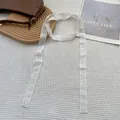 Dettaglio della sciarpa in pizzo bianco con ricamo floreale su tessuto a nido d'ape - Fiore a cinque petali