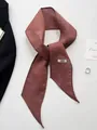 Detail of a dark red handmade linen scarf with a label on a clean white background - Burgundy
