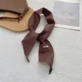 Detailed close-up of dark brown linen scarf with handmade label and natural fiber texture - Coffee