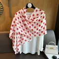 Detail of red polka dot silk scarf draped over a white blouse with elegant vintage vibes - Red Polka Dot