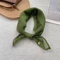 Detailed close-up of retro green silk scarf with delicate stitching and golden metal charm - Green