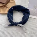 Detail of navy blue silk scarf with white heart patterns on a stylish prop background - Heart Navy