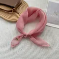 Detailed view of pink chiffon scarf with gold logo tag on a waffle texture background - Sakura Pink
