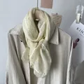 Detalle de bufanda de algodón beige con encaje ancho delicado drapeada sobre un abrigo - Beige