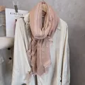 Detailed view of dust pink scarf with white lace trim layered over a beige trench coat - Bean Paste Pink