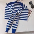 Detailed view of blue and white striped knit shawl with a brand label on soft fabric - Shawl / Striped Klein Blue