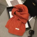 Detail showing orange wool scarf with chunky cable knit texture and 100% wool label - 170*30cm / Orange