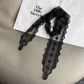 Detail of black lace scarf with floral embroidery and wavy edges on a fashion magazine - Black