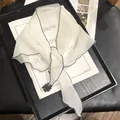 Detail of white semi-transparent scarf with dark gray edges and a black floral accent - 30x100 / White