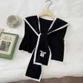 Detail of black knit shawl with white trim on wooden hanger with a cup of coffee - Black