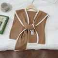 Detail eines braunen Strickschals mit weißem Rand und Markenetikett am Holzbügel - Khaki