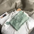Dettaglio della sciarpa verde con stampa di foglie tropicali e frange su camicia bianca - Stile Lungo / Verde