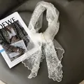 Elegant white floral lace scarf with embroidery and scalloped edges on leather background - Off White