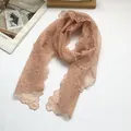 Detail of peach lace scarf with floral embroidery and elegant pearl accents on white - Pink