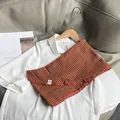 Close-up of orange-brown plaid cotton neck scarf on a white shirt with pleated texture - Orange