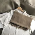Detailweergave van een kakibruine sjaal met textuur en franjes met wit overhemd - Khaki