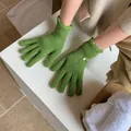 Detail of green knit gloves featuring scalloped cuffs and a decorative white button - Green